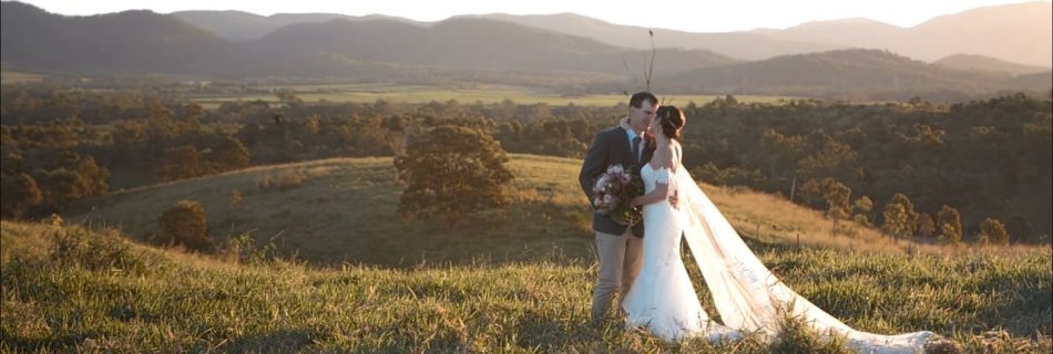 bride and groom standing in field embracing