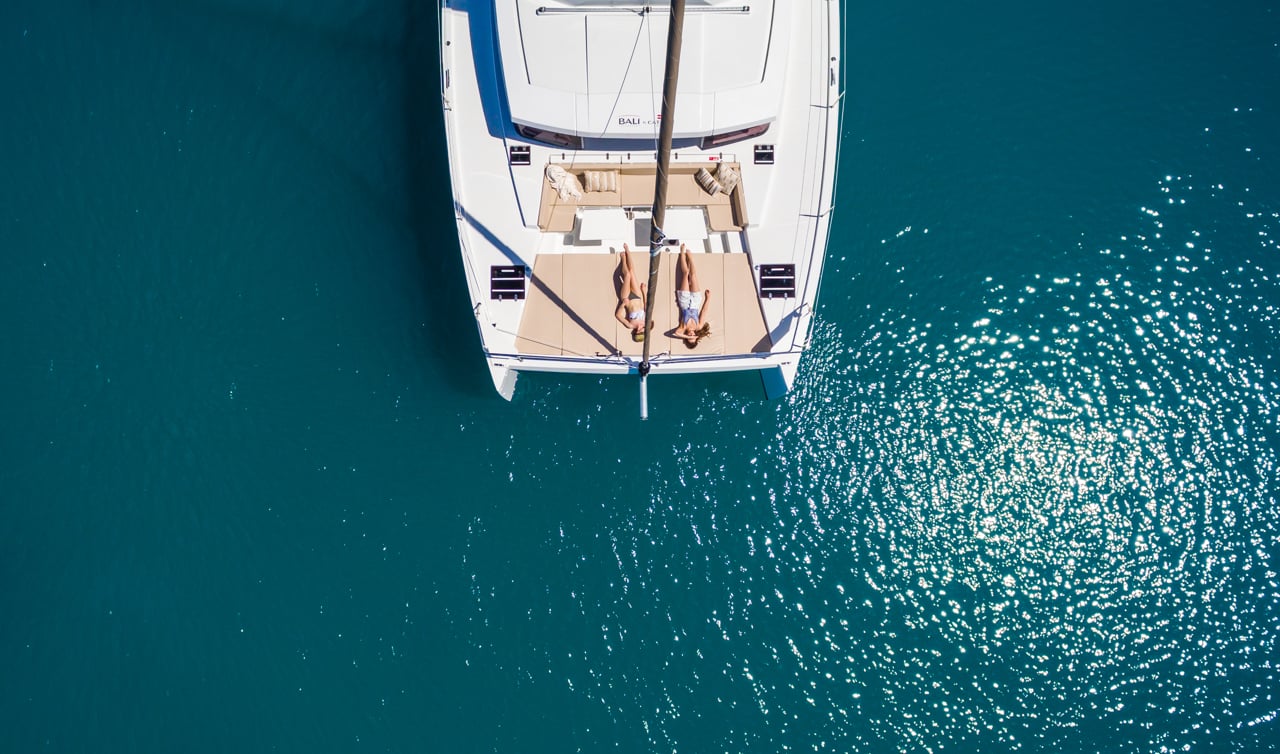 top down drone photo of catermeran with two girls sunbathing