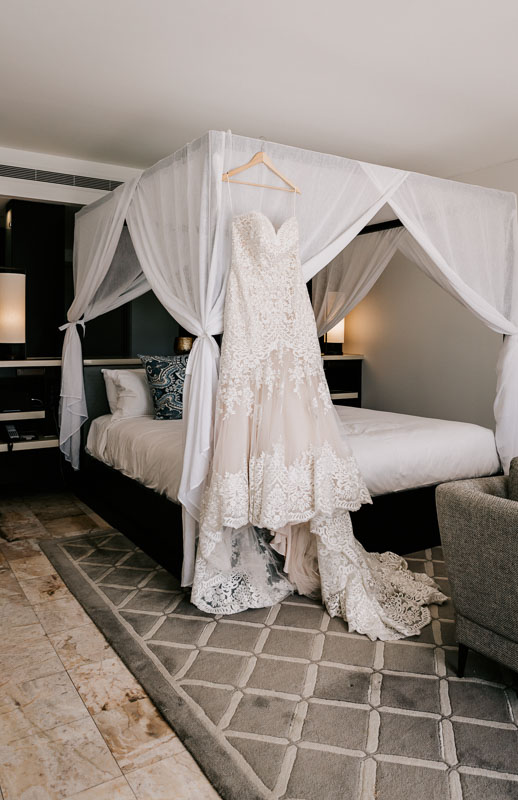 Hayman Island wedding dress hanging on 4 poster bed