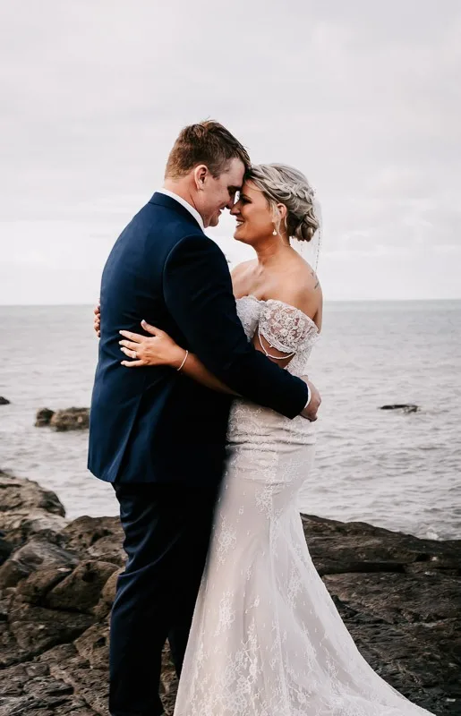 bride and groom next to the ocean on rocks