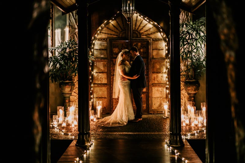 bride and groom in front of elephant doors with candles