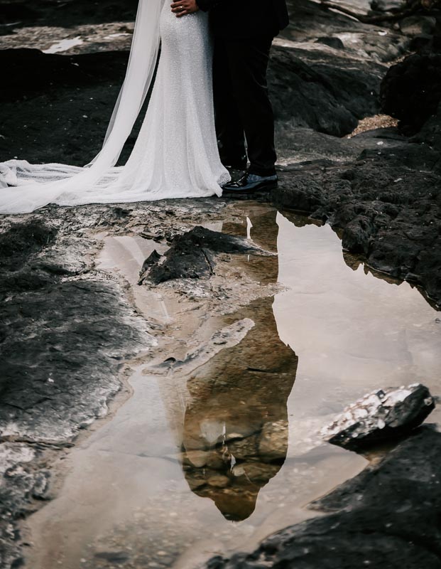 bride and groom reflection in ocean