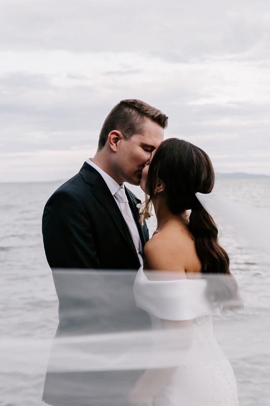 bride and groom kissing by the ocean
