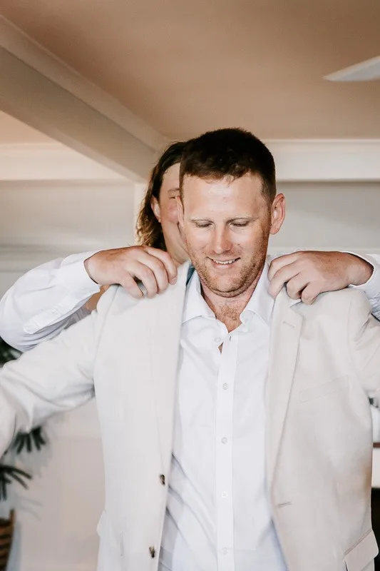groom putting on suit jacket