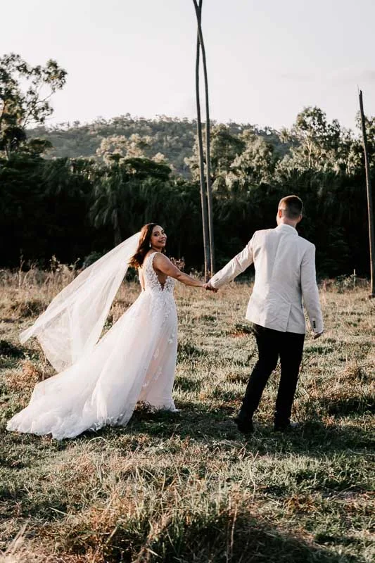 bride and groom walking in long grass