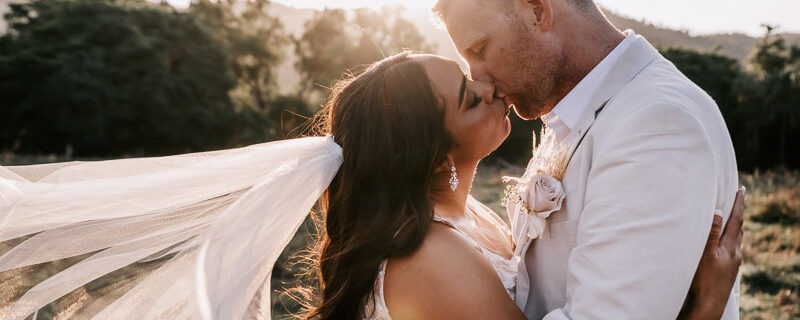 bride and groom kissing on sunset