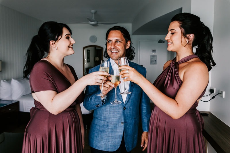 groom sharing champagne with adult daughters