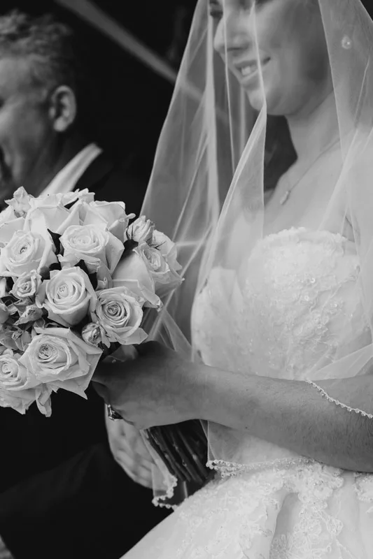 bride holding bouquet with father