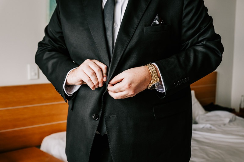 groom doing up buttons on jacket