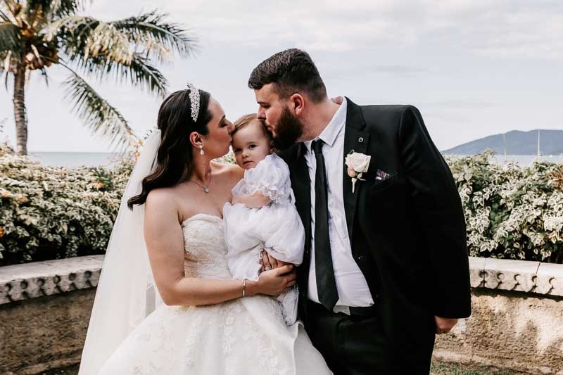 bride and groom kiss daughter