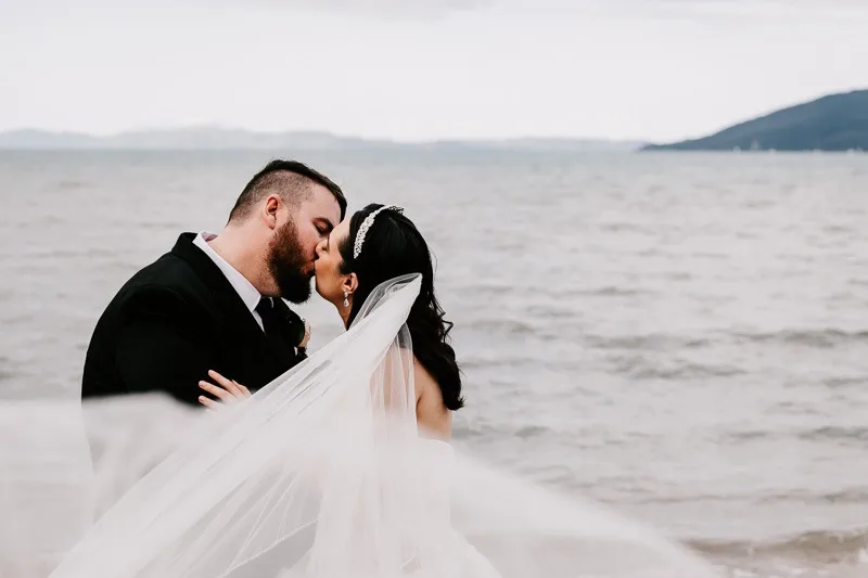 bride and groom kiss with veil