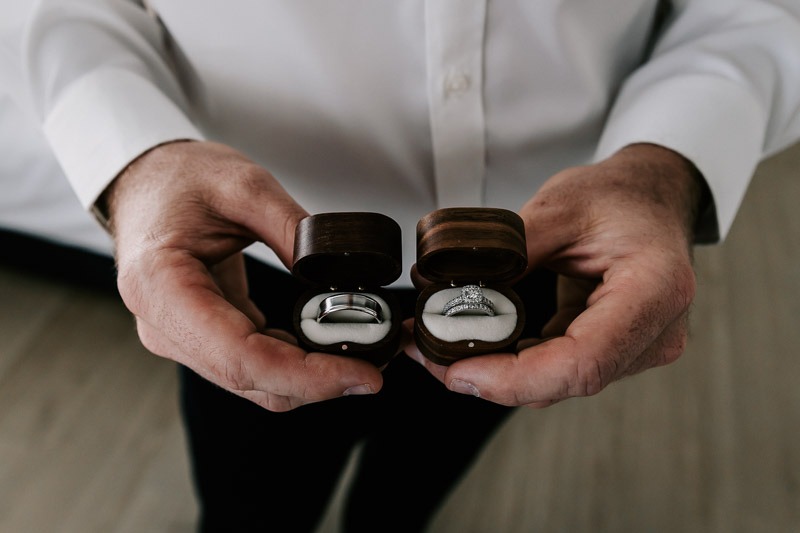 groom holding wedding rings in box