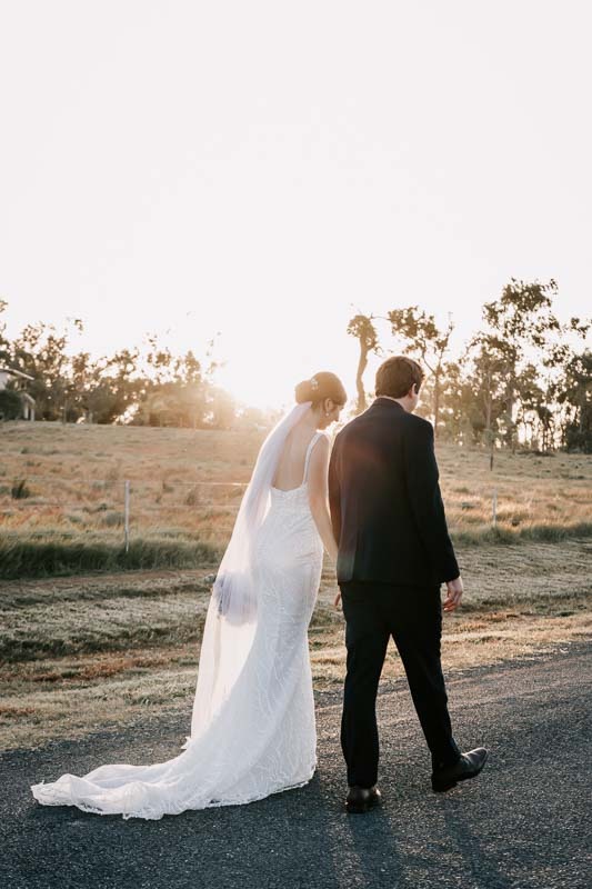 bride and groom holding hands on dirt road