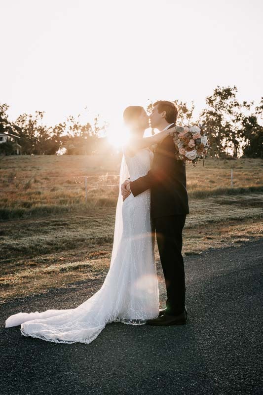 bride and groom hug and kiss at sunset