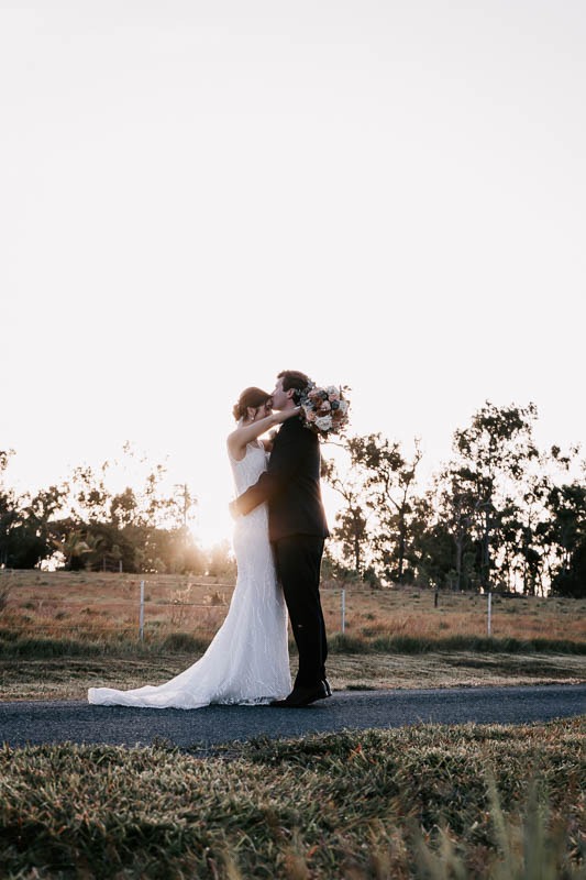 bride and groom on dirt road embracing