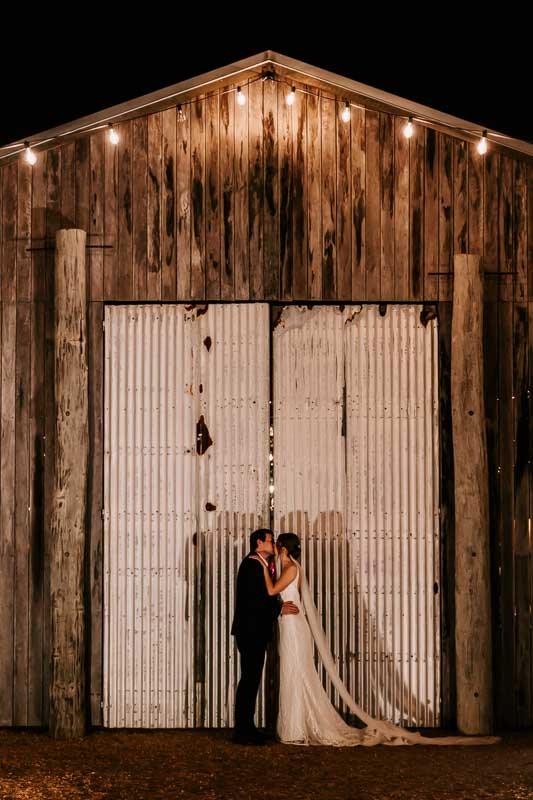 bride and groom kiss in front of large iron doors