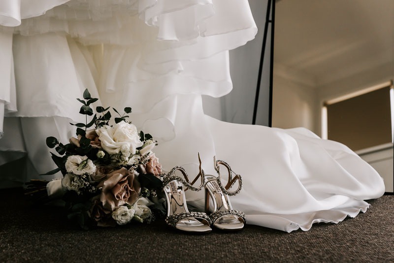 Brides shoes and bouquet at bottom of gown