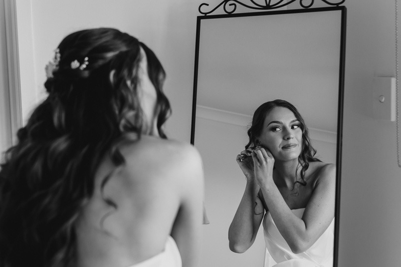 Bride putting on earrings in reflection of mirror