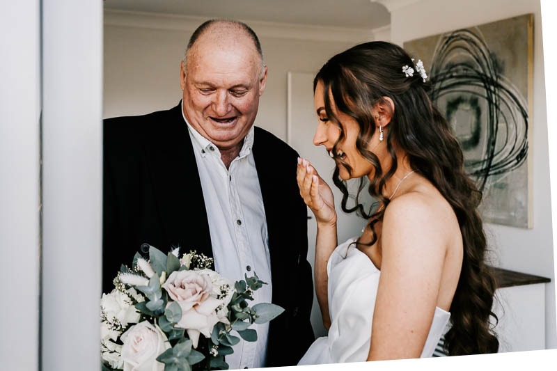 Brides father and bride admiring bouquet
