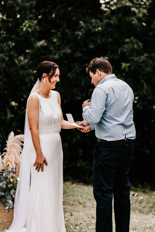 Groom reading vows to smiling bride