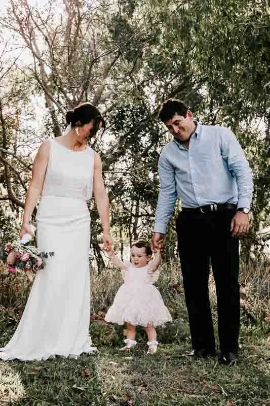 Bride & Groom hold hands of daughter