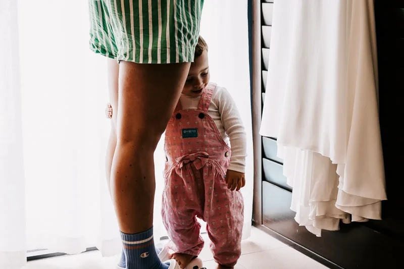 Child in pink overalls at brides feet