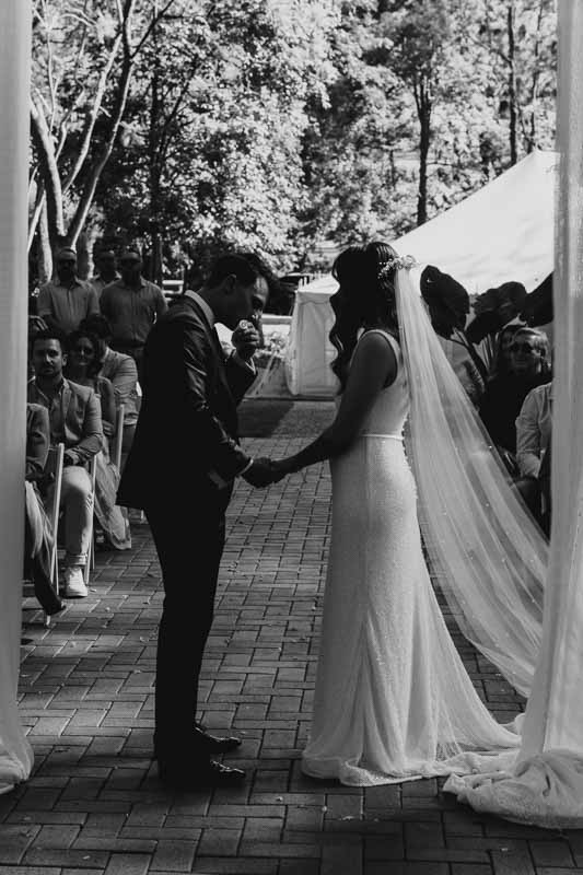 Bride & Groom holding hands at ceremony B&W