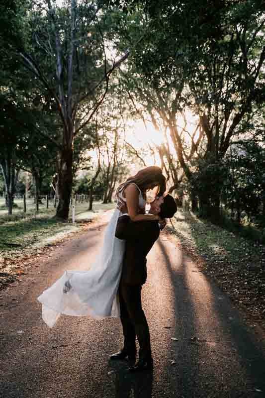 Groom lifts bride in sunset