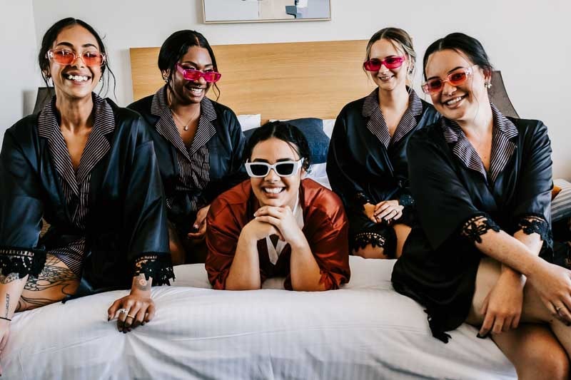Bride laying on bed with bridesmaids surround
