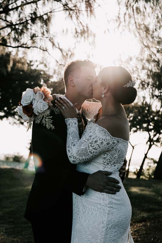 Bride & Groom kiss with sunset behind