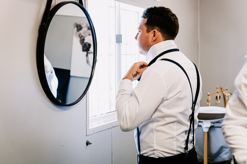 Groom adjusts tie in mirror