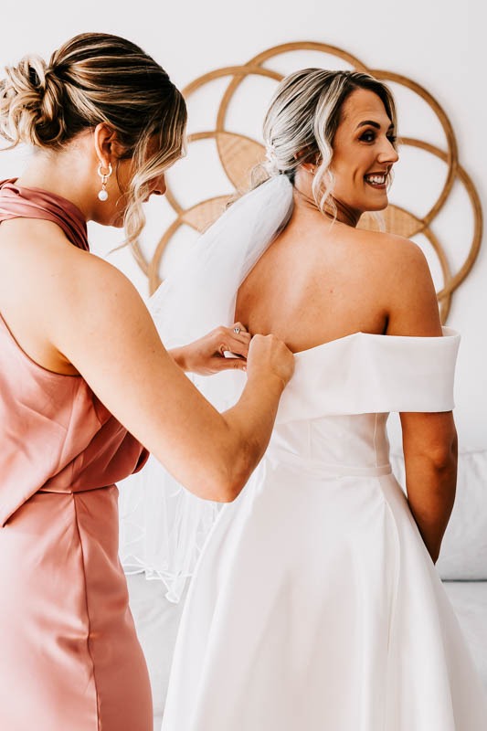 Bridesmaid assisting Bride with gown