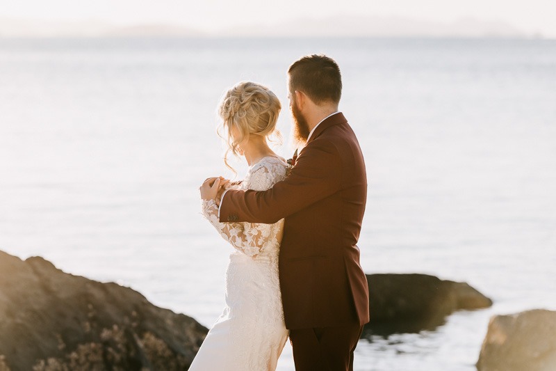 Bride & Groom embrace with beach sunset behind