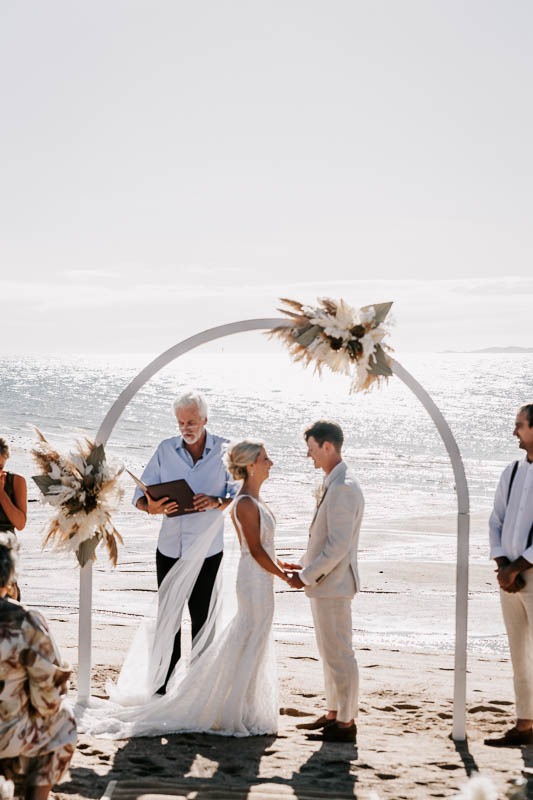 Bride & Groom hold hands at beach ceremony