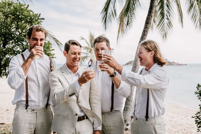 Groom cheers glasses with groomsmen