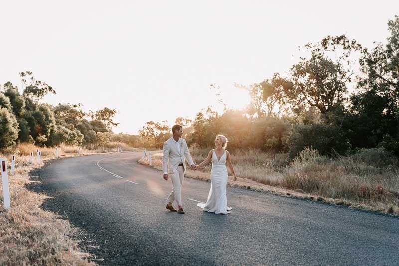 Bride & Groom walk on road holding hands