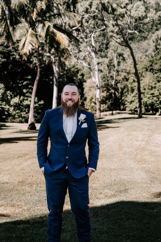 Groom smiling with bush behind