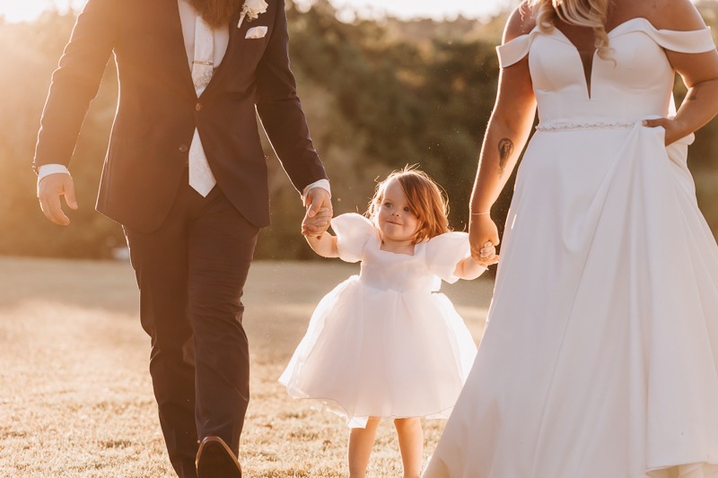 Bride & Groom holding hands with daughter