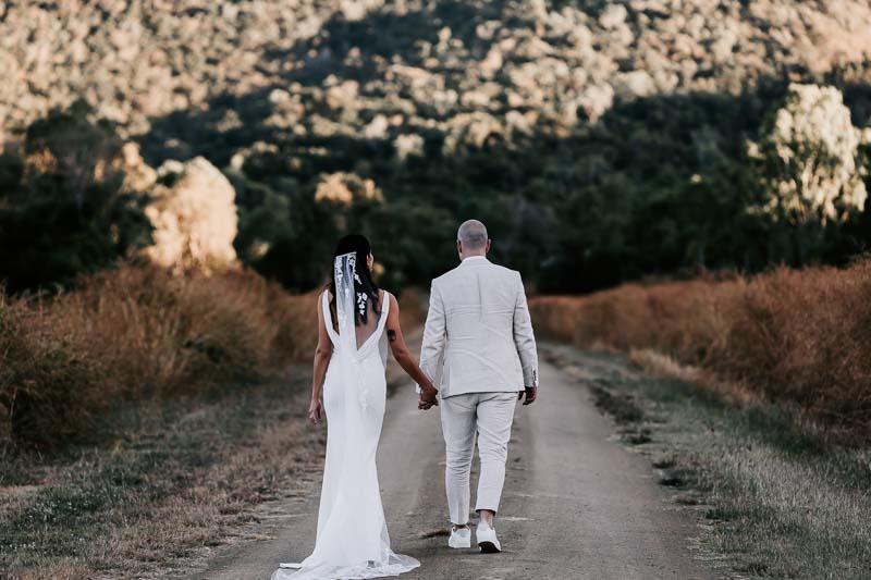 Bride & Groom hold hands and walk into mountains