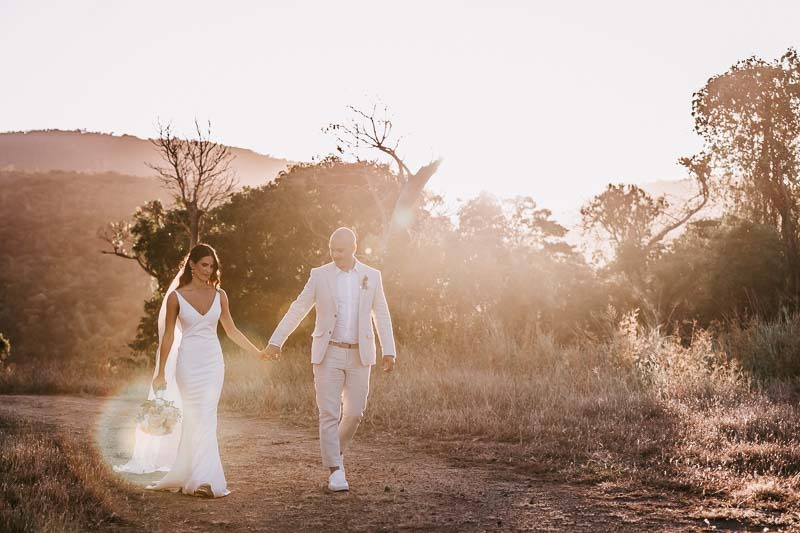 Bride & Groom hold hands at sunset