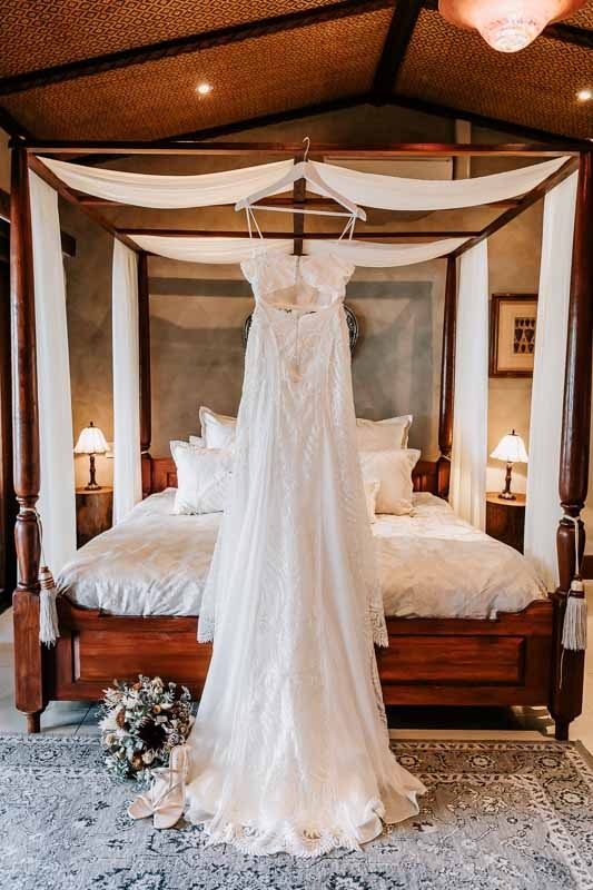 Brides gown hanging on bed
