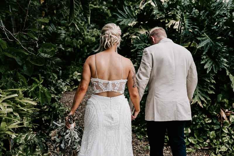 Bride & Groom hold hands and walk into rainforest