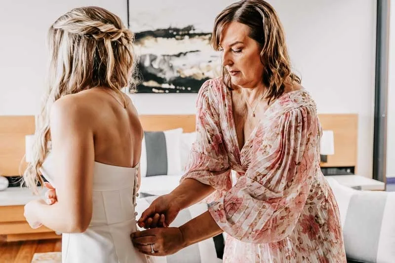 Mother zipping Brides dress