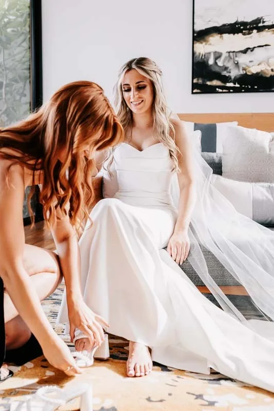 Bridesmaid helps Bride with shoes