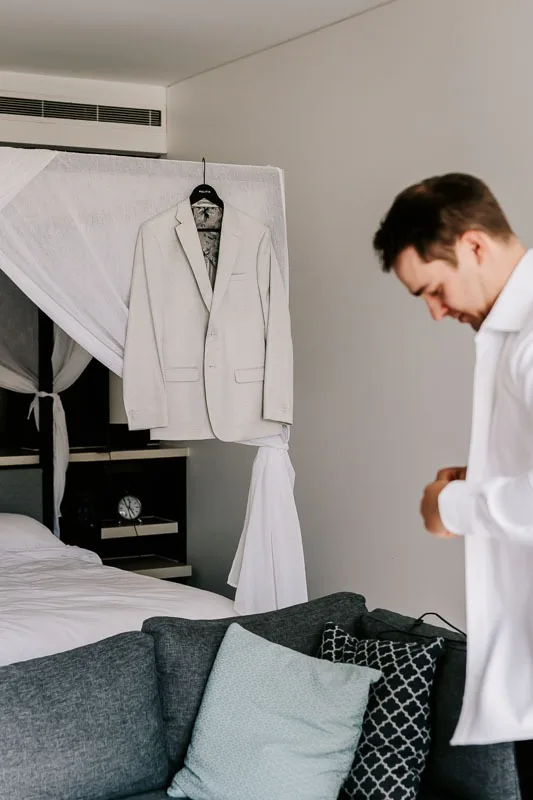 Groom putting on shirt