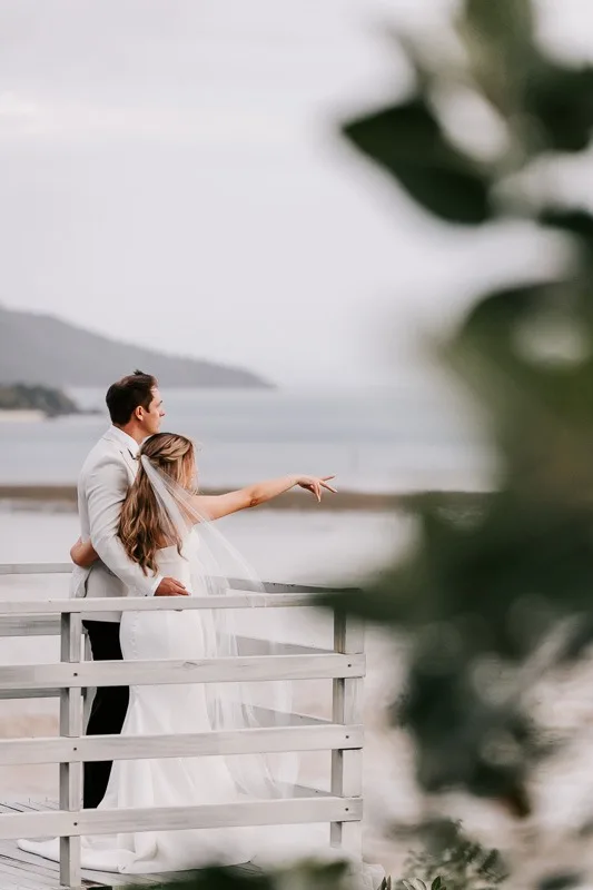 Bride & Groom point towards ocean