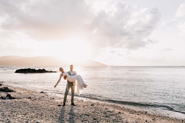 Groom holding bride on beach