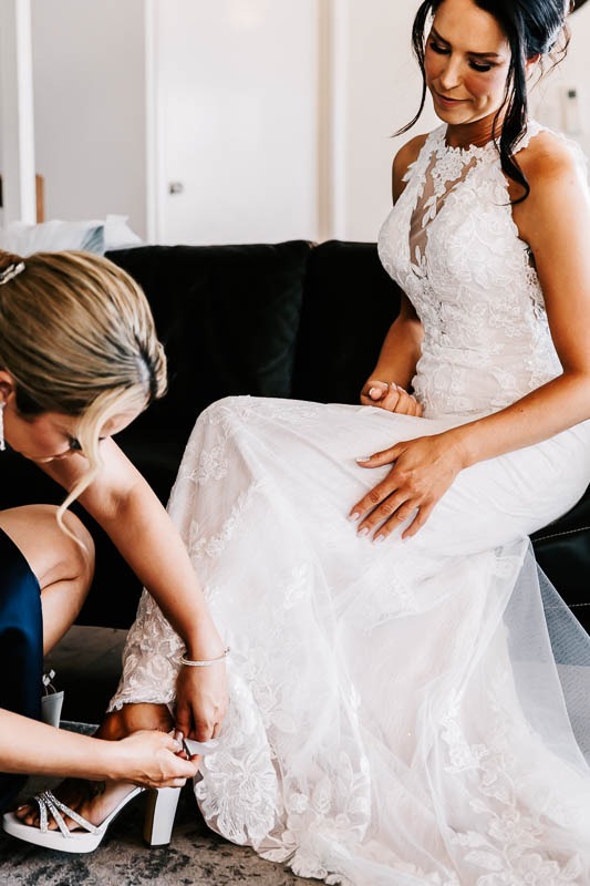 Bridesmaid helps bride with shoes