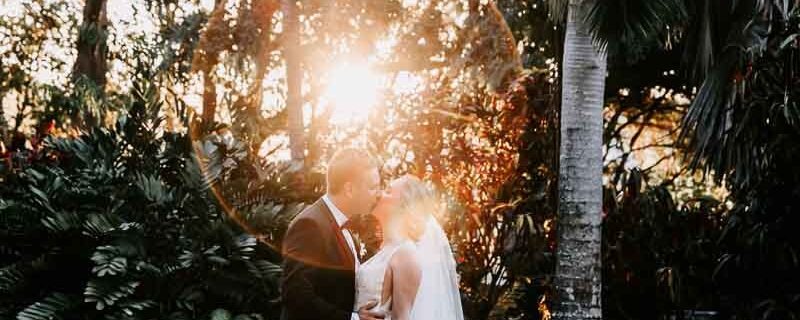 Bride & Groom embrace and kiss with sun flare