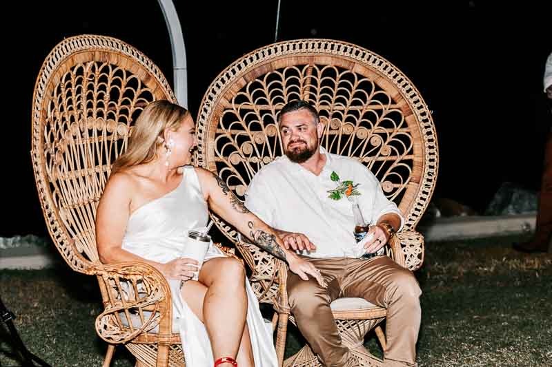 Bride & Groom holding hands sitting in cane chairs